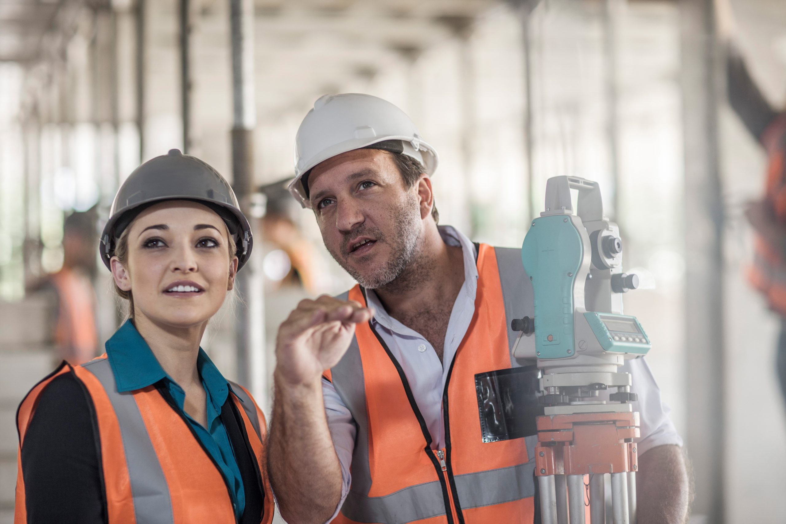 Surveyor explaining to female builder on construction site